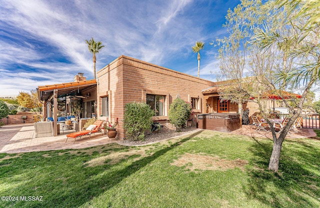 rear view of property with a lawn, a patio area, ceiling fan, and a hot tub