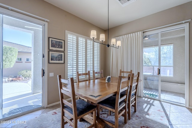 tiled dining area with ceiling fan with notable chandelier