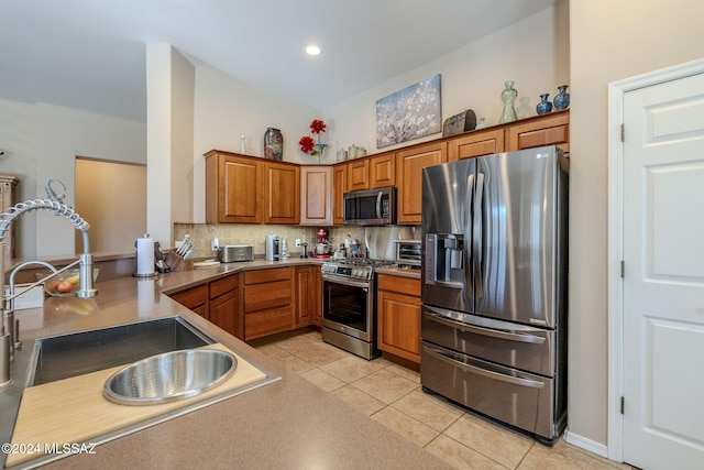 kitchen with sink, kitchen peninsula, decorative backsplash, light tile patterned flooring, and appliances with stainless steel finishes