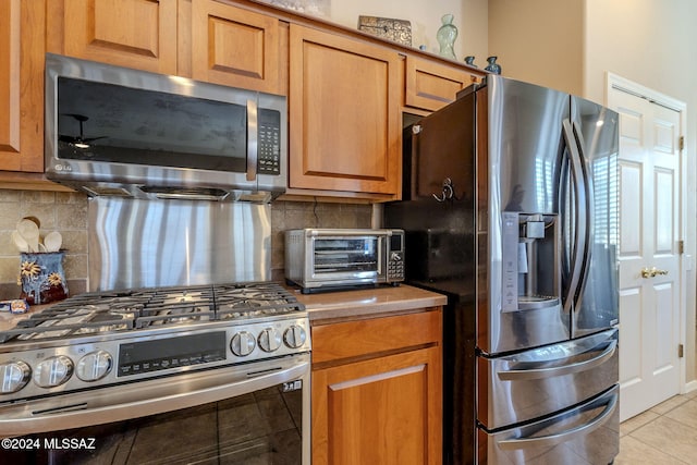 kitchen with decorative backsplash, appliances with stainless steel finishes, and light tile patterned floors