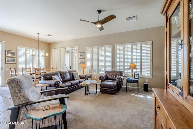 living room with ceiling fan with notable chandelier, light carpet, and a wealth of natural light