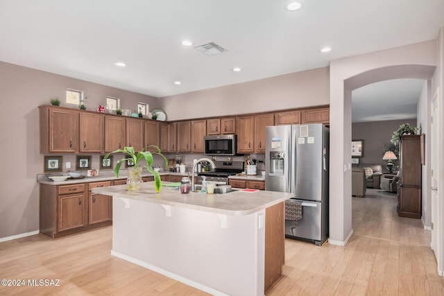 kitchen featuring a kitchen bar, light hardwood / wood-style flooring, an island with sink, and stainless steel appliances