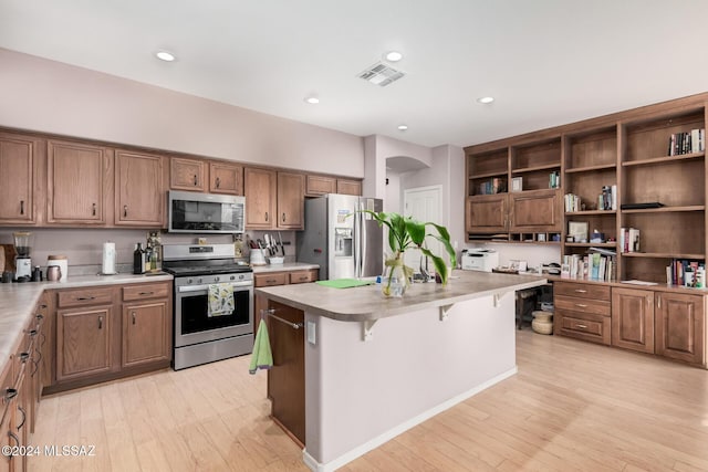 kitchen featuring a kitchen breakfast bar, a center island, light wood-type flooring, and appliances with stainless steel finishes