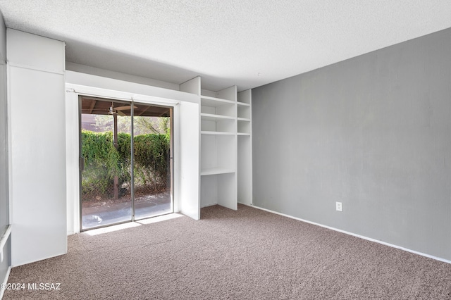 carpeted empty room with a textured ceiling