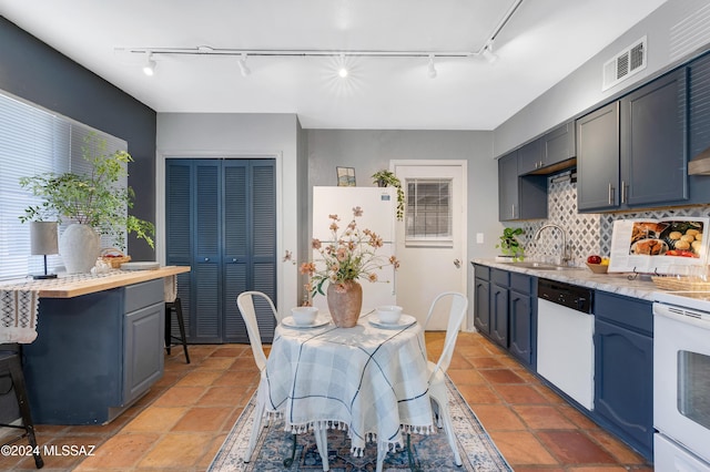 kitchen with sink, white appliances, blue cabinetry, and backsplash