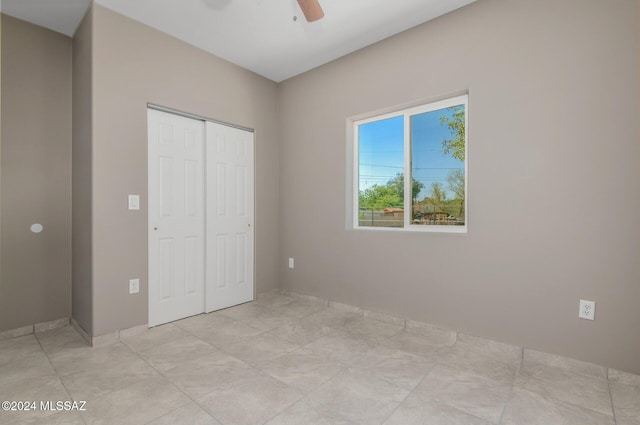 unfurnished bedroom with ceiling fan and a closet