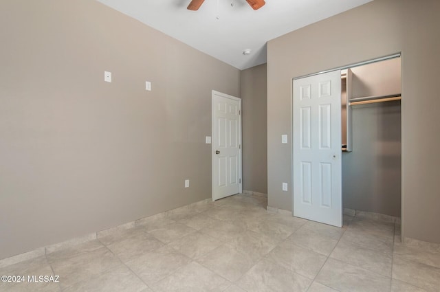 unfurnished bedroom featuring ceiling fan, vaulted ceiling, light tile patterned flooring, and a closet