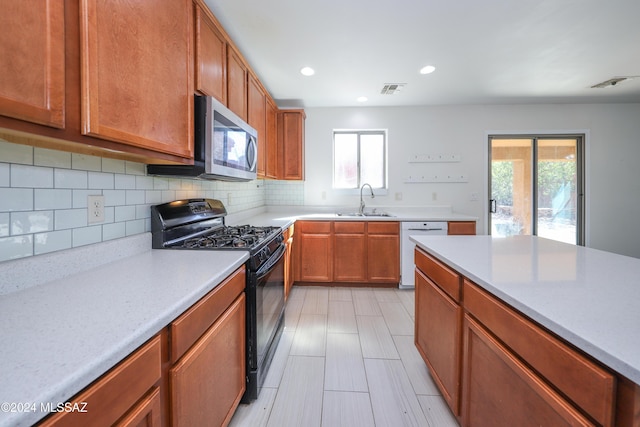 kitchen featuring backsplash, black range with gas stovetop, sink, and white dishwasher