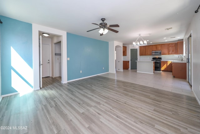 unfurnished living room featuring ceiling fan with notable chandelier, light wood-type flooring, and sink