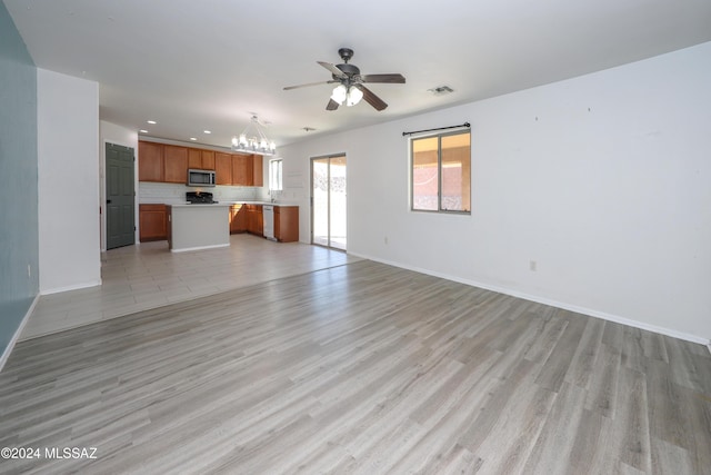 unfurnished living room with ceiling fan with notable chandelier and light wood-type flooring