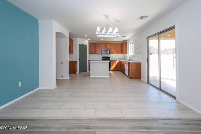 kitchen with sink, stainless steel appliances, backsplash, a chandelier, and pendant lighting