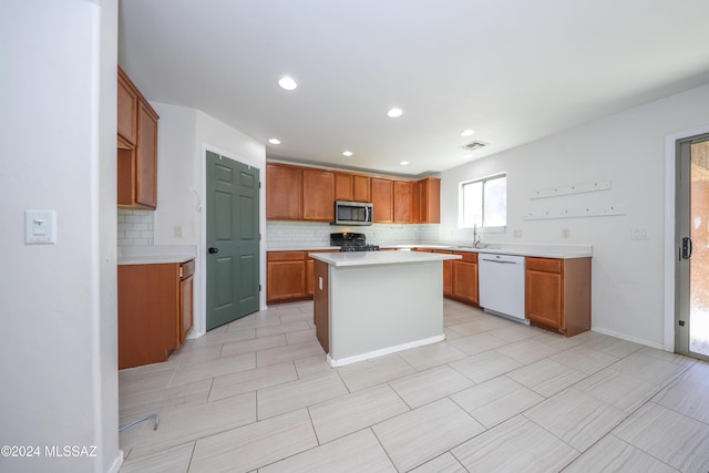 kitchen with tasteful backsplash, white dishwasher, sink, black gas stove, and a kitchen island