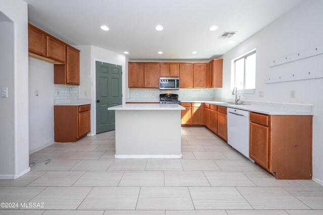 kitchen featuring dishwasher, black gas stove, sink, tasteful backsplash, and a kitchen island