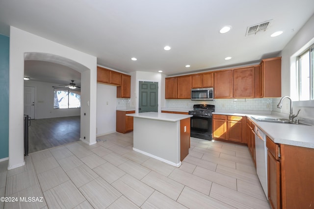 kitchen featuring dishwasher, sink, ceiling fan, a kitchen island, and gas stove