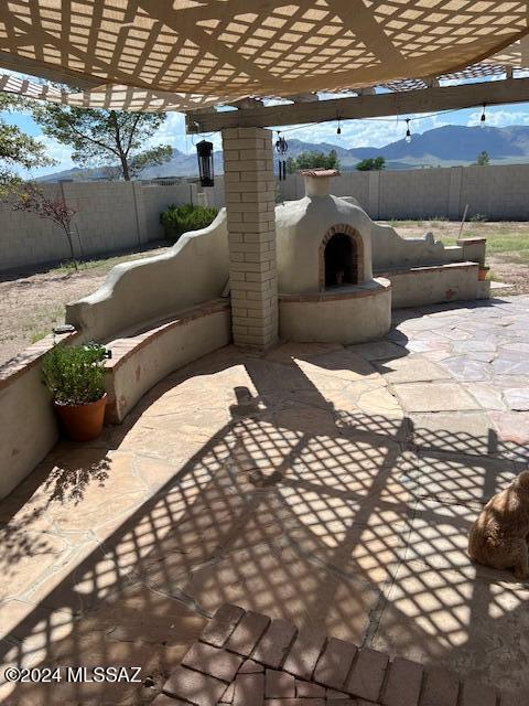 view of patio / terrace featuring a pergola, a mountain view, and exterior fireplace