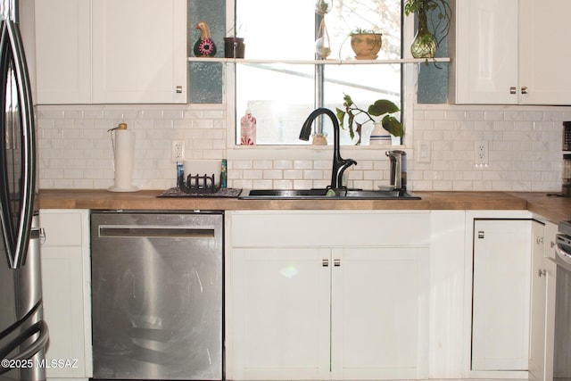 kitchen featuring decorative backsplash, refrigerator, sink, dishwasher, and white cabinetry