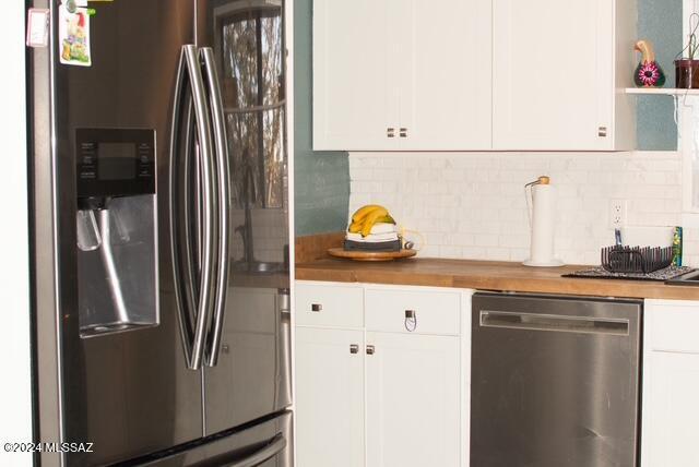 kitchen featuring wood counters, appliances with stainless steel finishes, tasteful backsplash, and white cabinetry