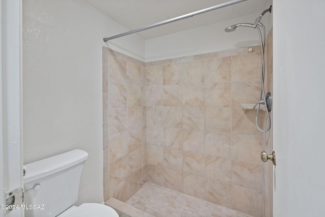 bathroom with a tile shower and toilet