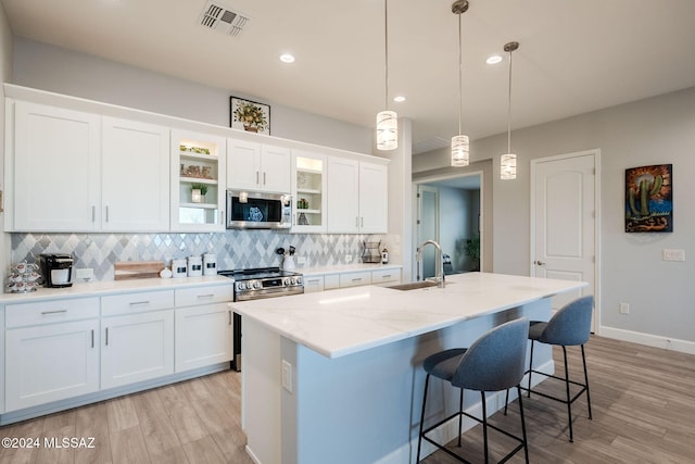 kitchen featuring white cabinets, decorative light fixtures, stainless steel appliances, and sink