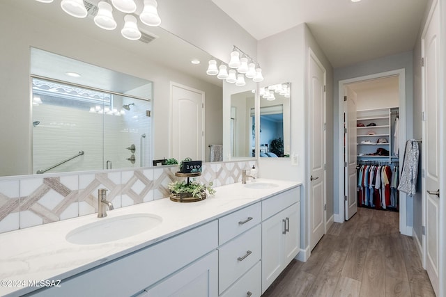 bathroom featuring hardwood / wood-style floors, vanity, an enclosed shower, and tasteful backsplash