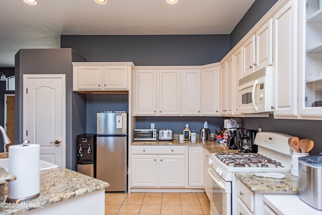 kitchen with white cabinetry, light stone countertops, white appliances, and light tile patterned floors