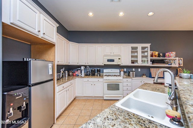 kitchen with white cabinetry, sink, light stone countertops, white appliances, and light tile patterned floors