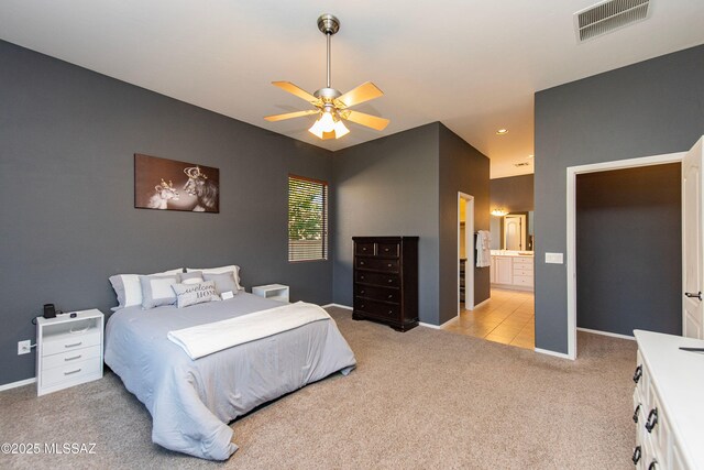 bedroom with ceiling fan, ensuite bathroom, and light carpet