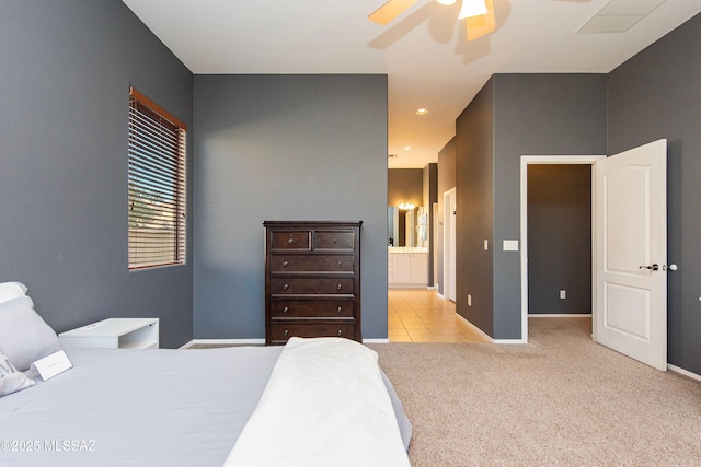 bedroom with connected bathroom, light colored carpet, and ceiling fan