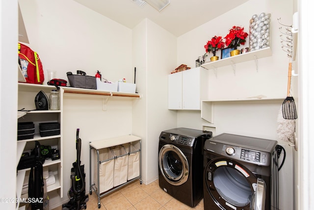 washroom with washing machine and dryer, light tile patterned flooring, and cabinets