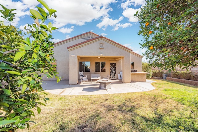 back of house featuring a lawn, ceiling fan, area for grilling, a patio area, and an outdoor fire pit