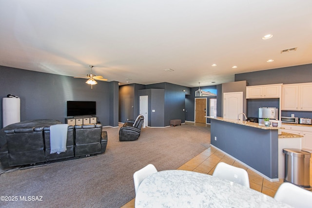 carpeted living room featuring ceiling fan and sink