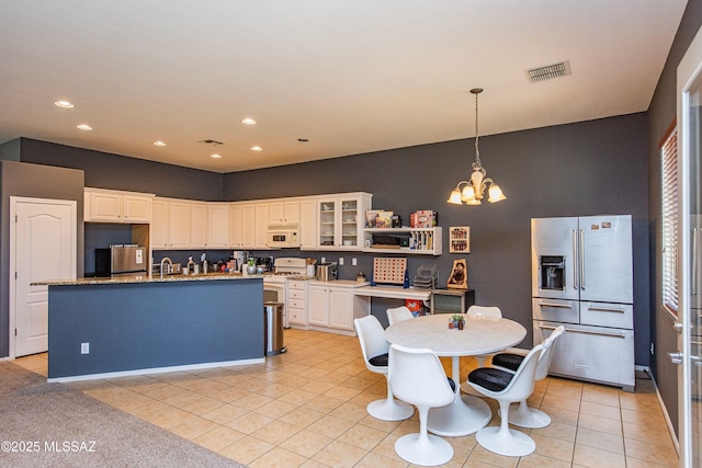 kitchen featuring a center island with sink, stainless steel fridge with ice dispenser, light tile patterned floors, white cabinetry, and a chandelier