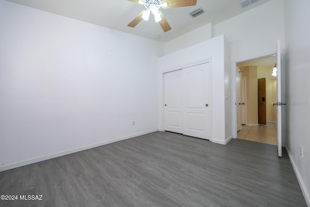 unfurnished bedroom featuring dark hardwood / wood-style flooring, a closet, and ceiling fan