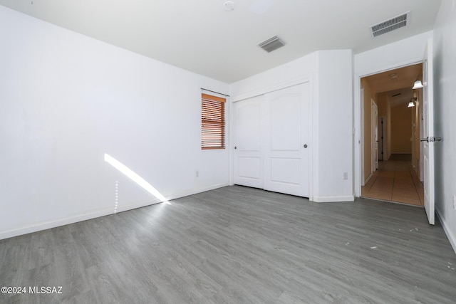 unfurnished bedroom with dark hardwood / wood-style flooring and a closet