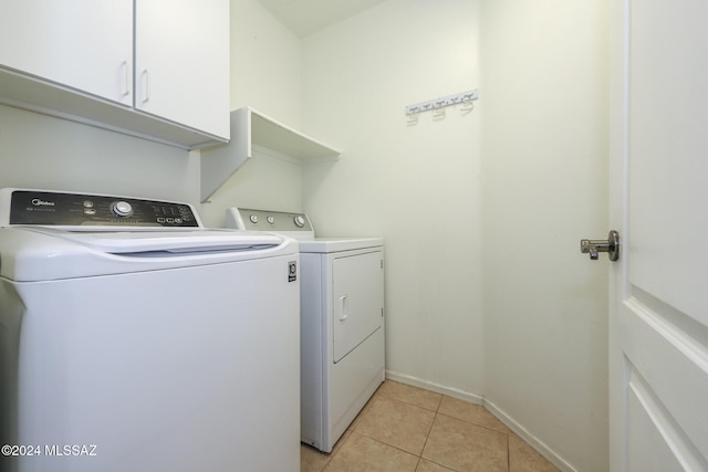 clothes washing area featuring cabinets, light tile patterned floors, and separate washer and dryer