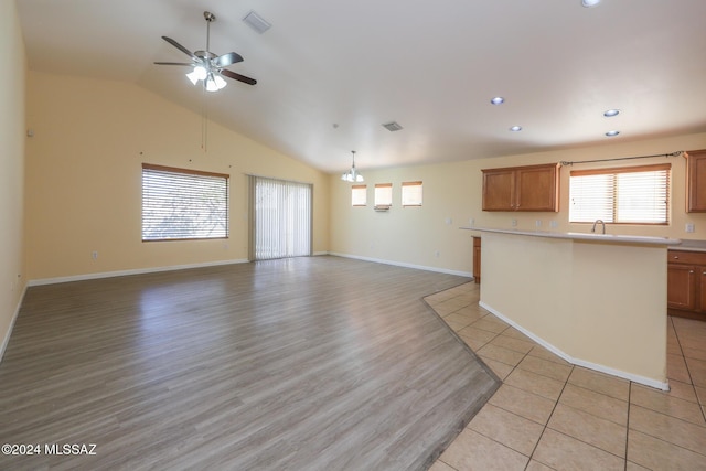 unfurnished living room featuring ceiling fan, lofted ceiling, sink, and light tile patterned floors