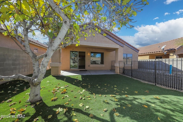 rear view of house featuring a lawn and a patio