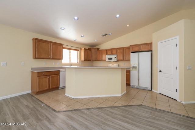 kitchen with a center island, light wood-type flooring, white appliances, and vaulted ceiling