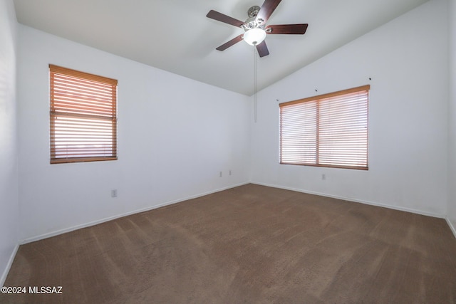 empty room with dark colored carpet, ceiling fan, and vaulted ceiling