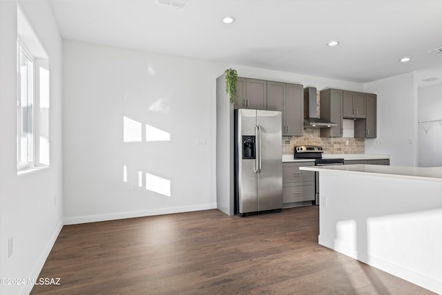 kitchen featuring decorative backsplash, dark hardwood / wood-style flooring, stainless steel appliances, wall chimney range hood, and gray cabinets