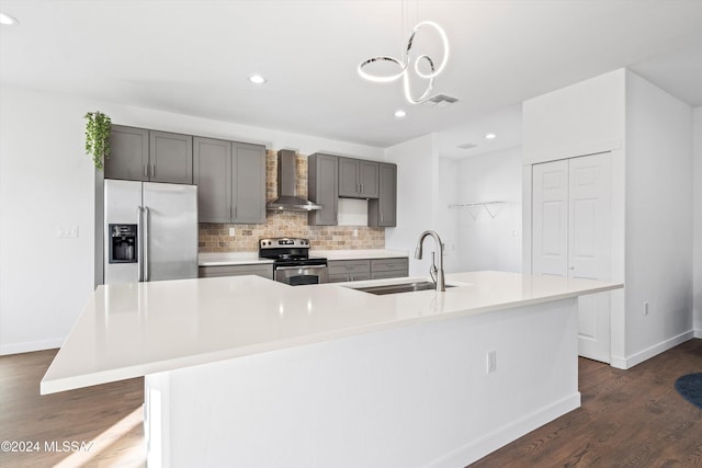 kitchen with sink, hanging light fixtures, wall chimney range hood, a spacious island, and appliances with stainless steel finishes