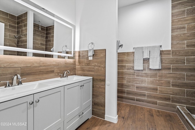 bathroom with a shower, vanity, hardwood / wood-style flooring, and tile walls