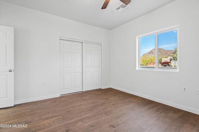 unfurnished bedroom with ceiling fan, dark wood-type flooring, and a closet