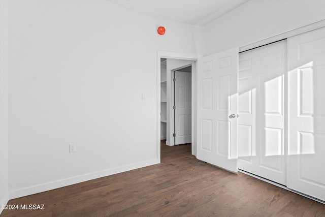unfurnished bedroom featuring a closet and dark wood-type flooring