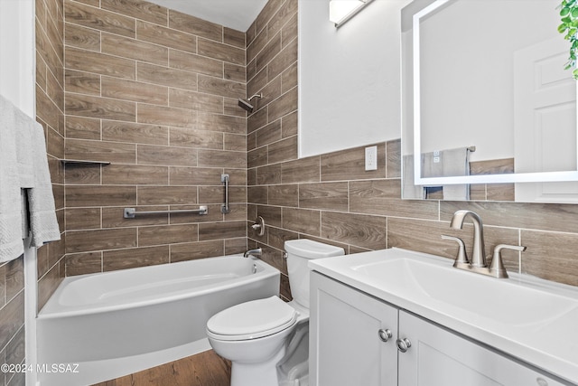 full bathroom featuring vanity, tiled shower / bath, hardwood / wood-style flooring, toilet, and tile walls