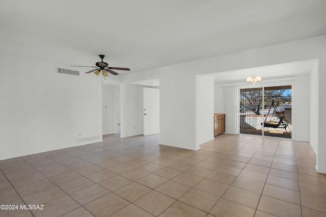 tiled spare room with ceiling fan with notable chandelier