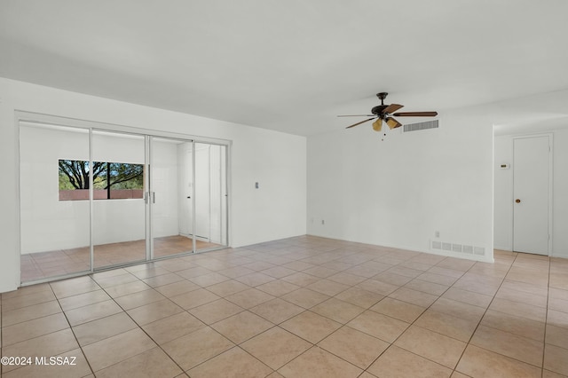 empty room with ceiling fan and light tile patterned flooring