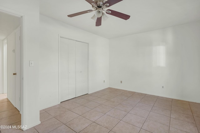 unfurnished bedroom featuring ceiling fan, light tile patterned floors, and a closet