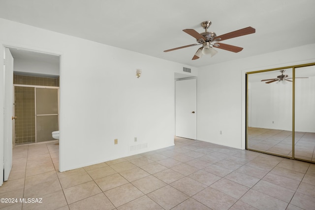 unfurnished bedroom with connected bathroom, a closet, ceiling fan, and light tile patterned flooring