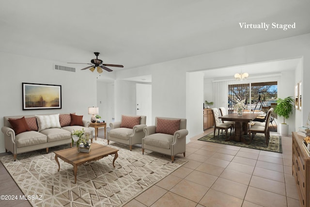 living room with ceiling fan with notable chandelier and light tile patterned floors